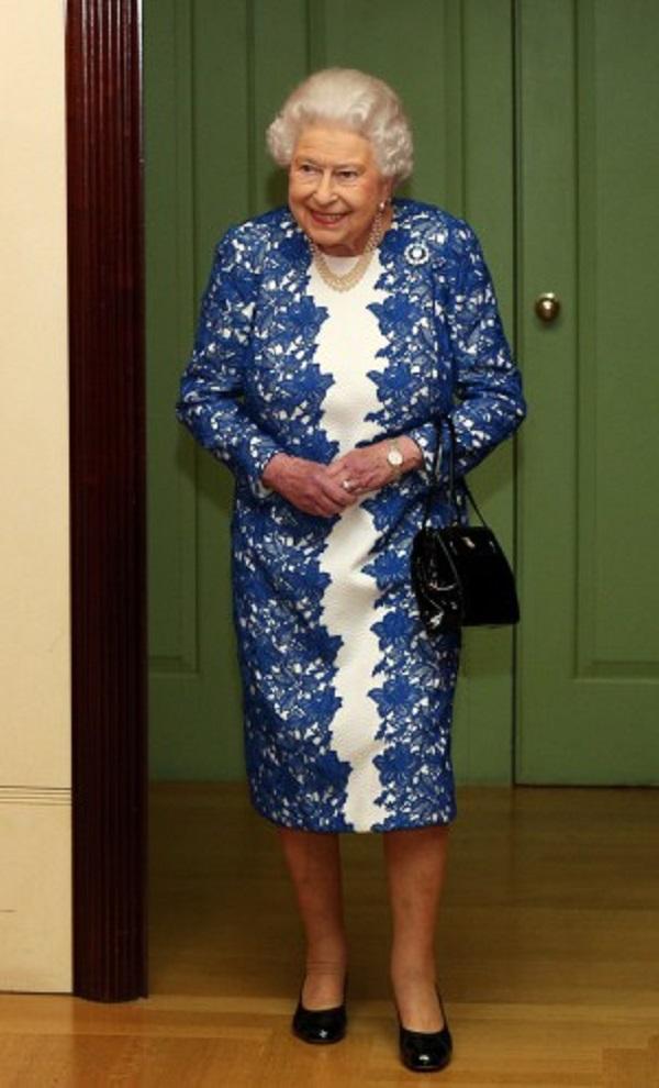 Королева Елизавета II на приеме в ярком кружевном платье и с бокалом